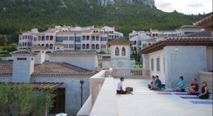 sales incentive trip with group doing yoga among spanish-style buildings