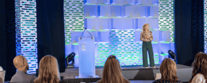 woman onstage presenting to crowd at a conference