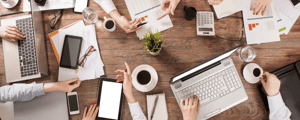 meeting planning checklist with group of people sitting around a table with papers and laptops to plan a meeting